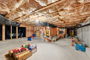 Unfinished basement featuring concrete flooring, exposed wood framing, and ceiling insulation