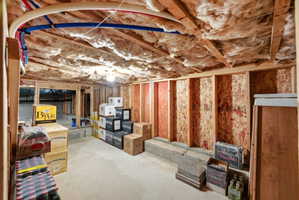 Unfinished basement featuring exposed wood joists, ceiling insulation, and concrete flooring