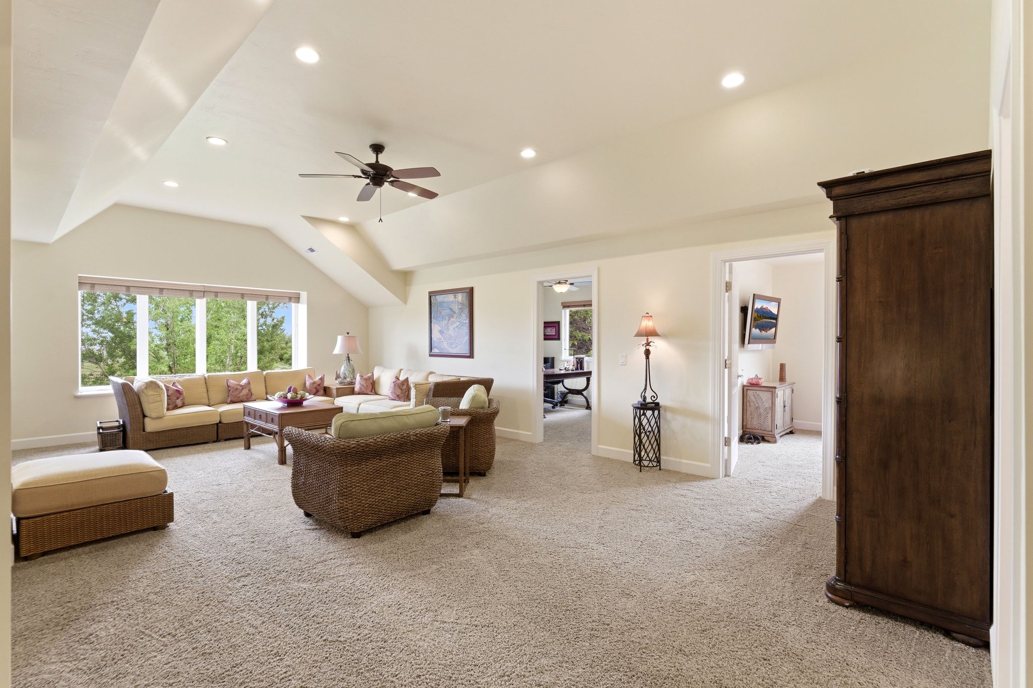 Spacious room featuring vaulted ceilings, recessed lighting, a ceiling fan, and carpeted flooring