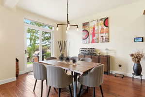 Dining area with wood-finish flooring and a contemporary linear chandelier