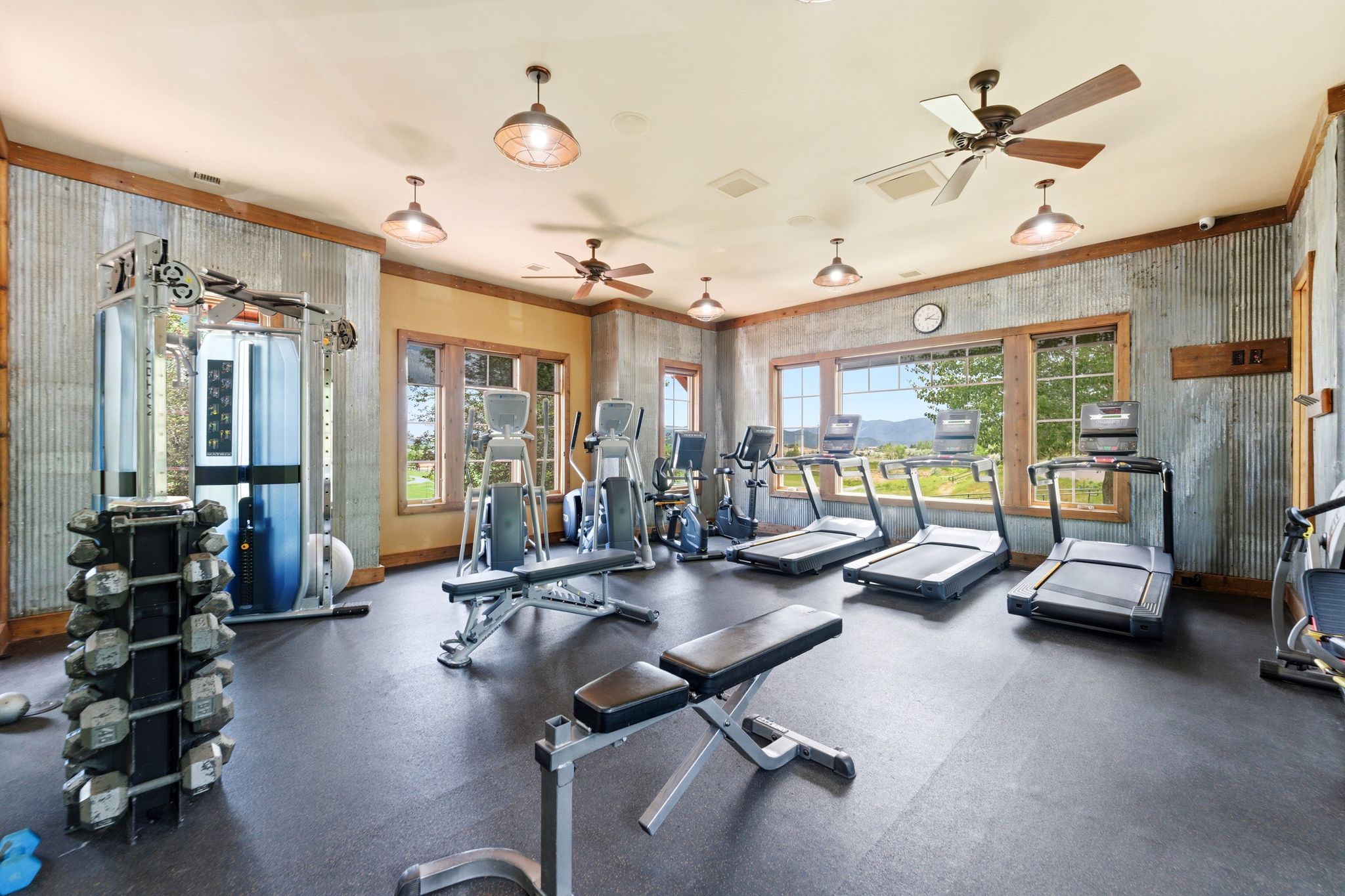 Dedicated fitness space featuring rubber flooring, corrugated metal wall accents, exposed wood trim, and multiple windows