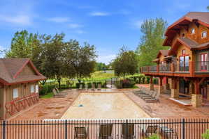 Outdoor swimming pool with a surrounding hardscape patio, bordered by a black metal fence