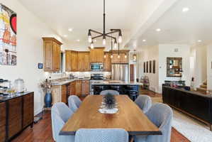 Open-concept living space featuring wood-finish flooring, a kitchen with natural wood cabinetry and stainless steel appliances, a central island with bar seating, and recessed lighting throughout