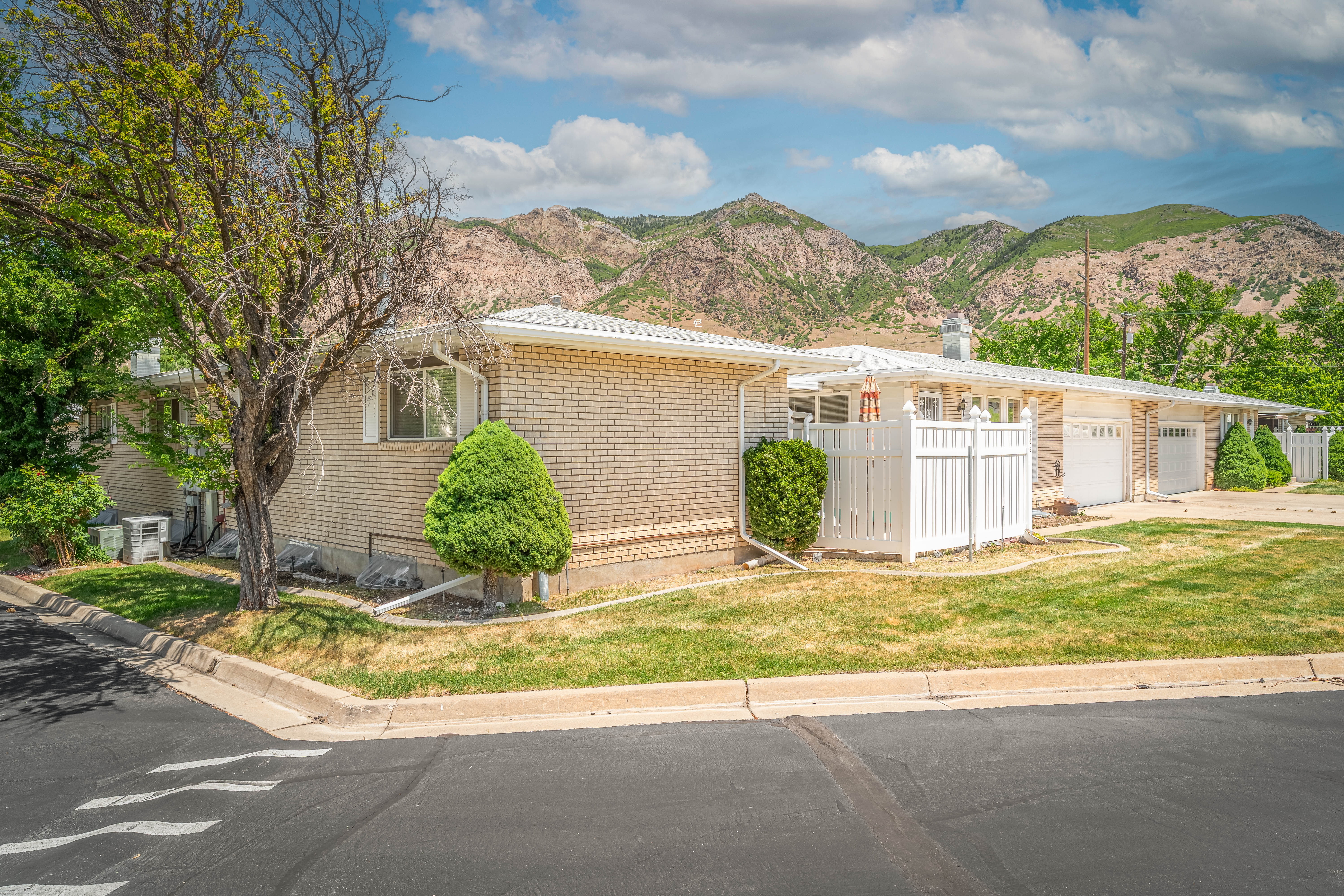 Brick exterior property with white trim and a white picket fence, set against a mountain backdrop