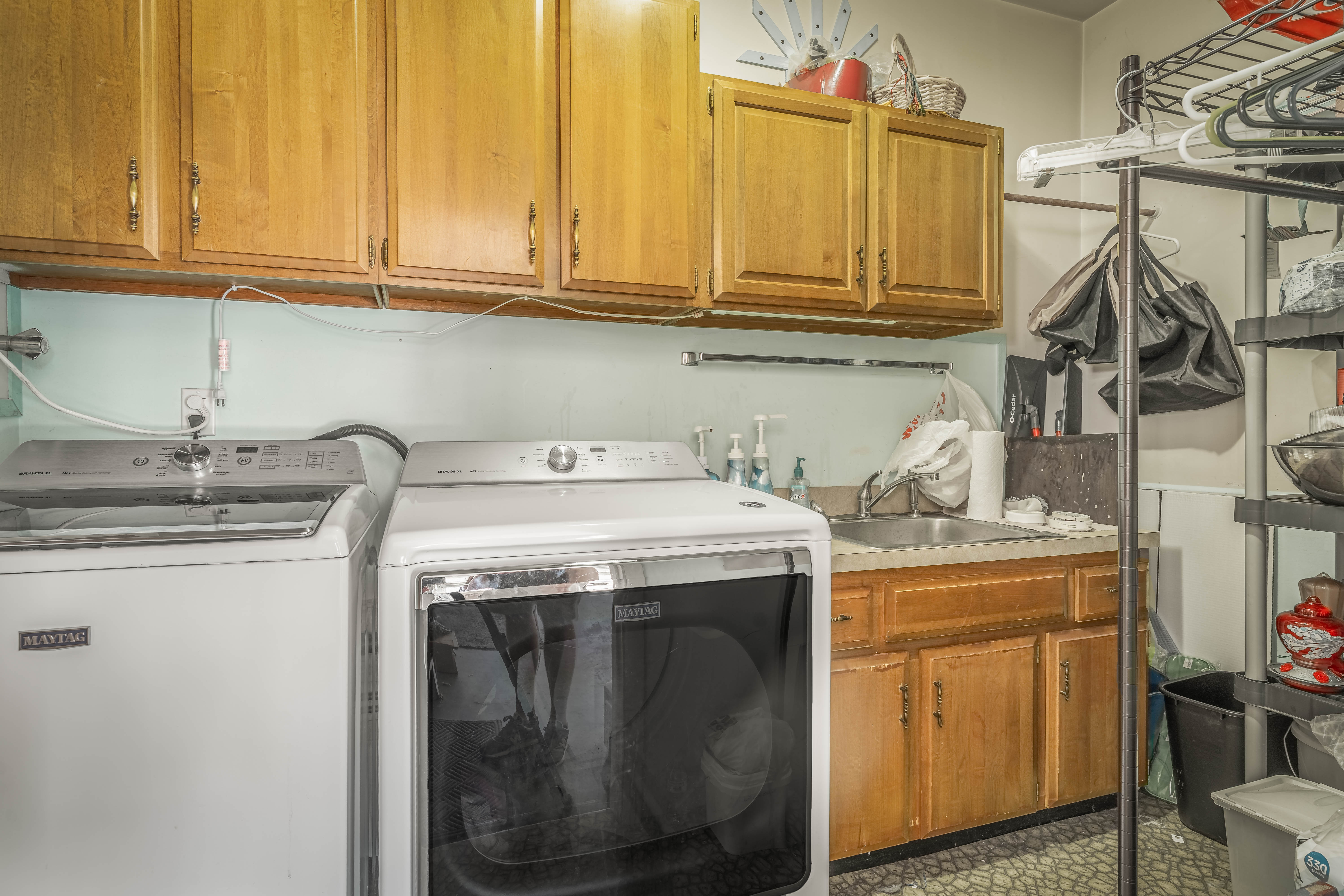 Utility area featuring wood-finish cabinetry, a stainless steel sink, and durable tile flooring