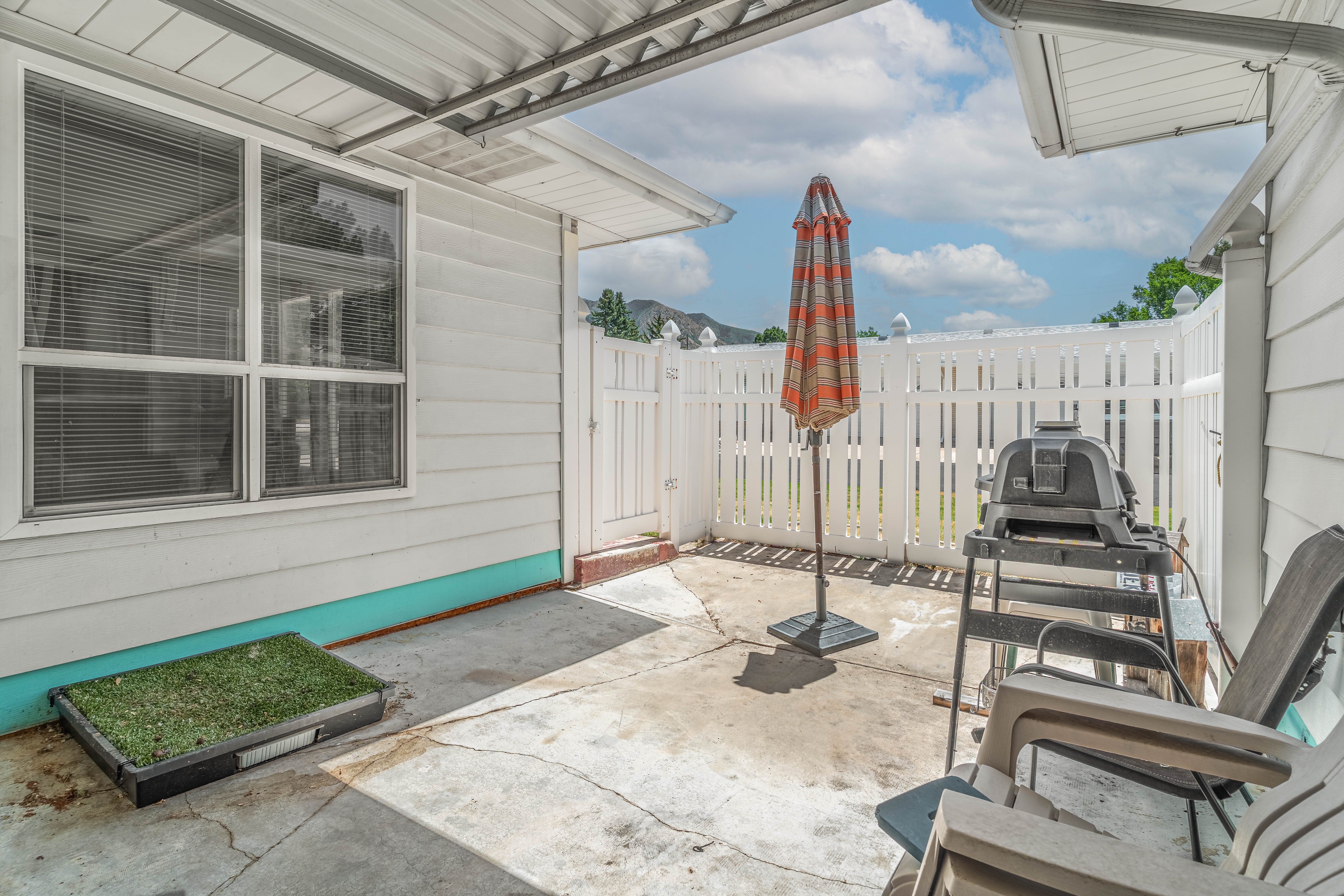 Covered patio area featuring a concrete slab, white siding, and a white privacy fence