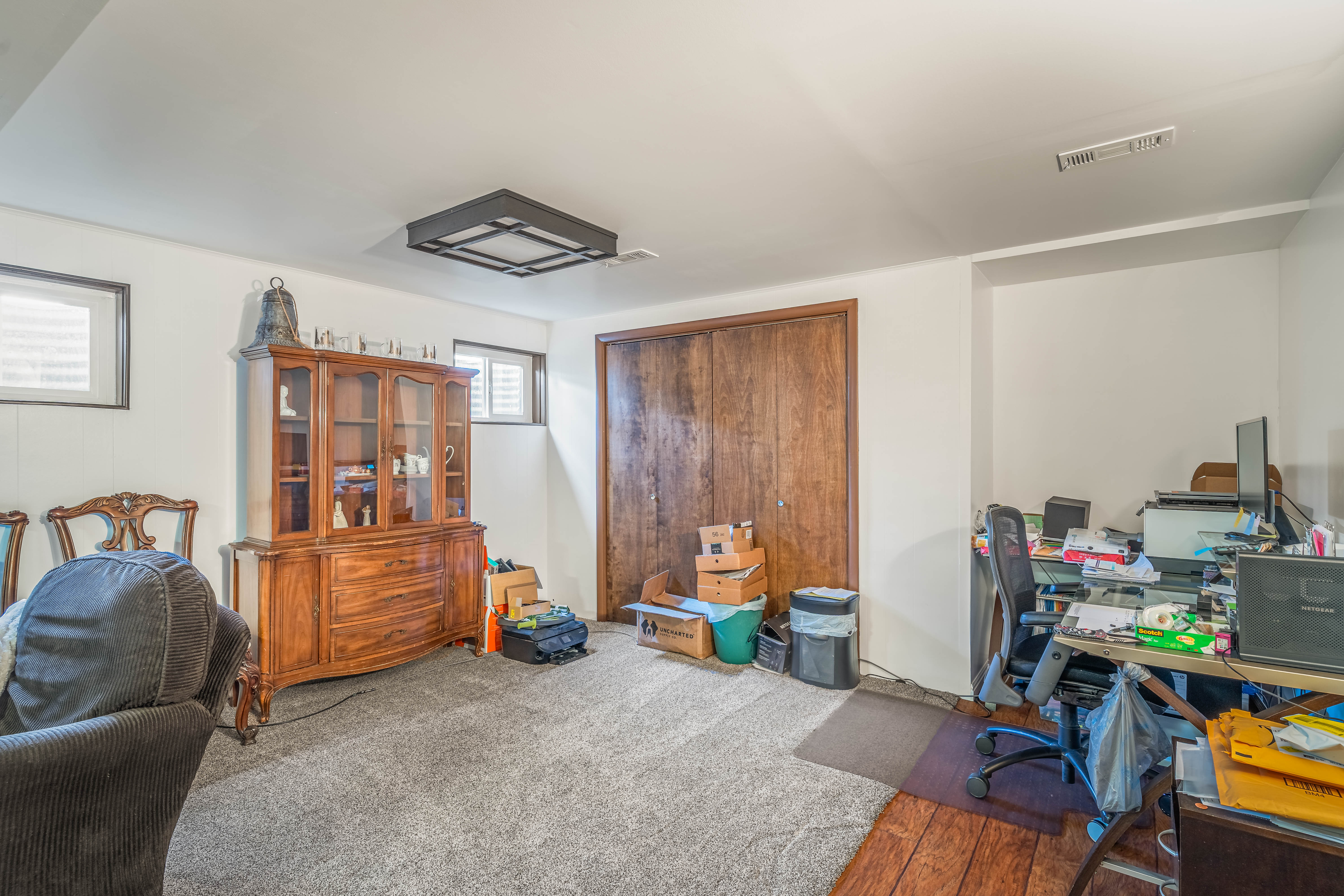 Spacious room featuring light gray carpet flooring, white walls, and a contemporary ceiling light fixture
