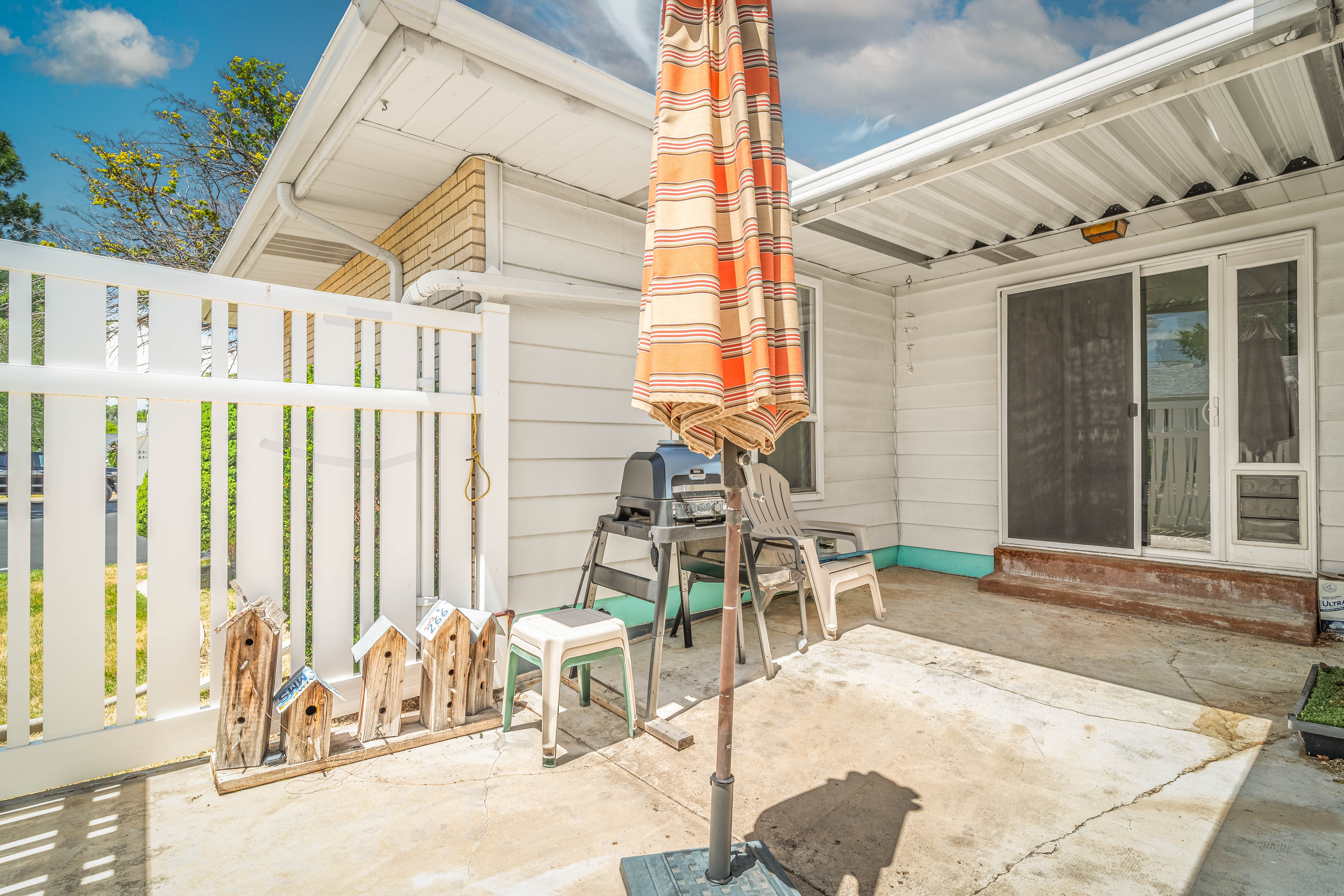 Exterior patio with concrete flooring, white horizontal siding, and a white privacy fence