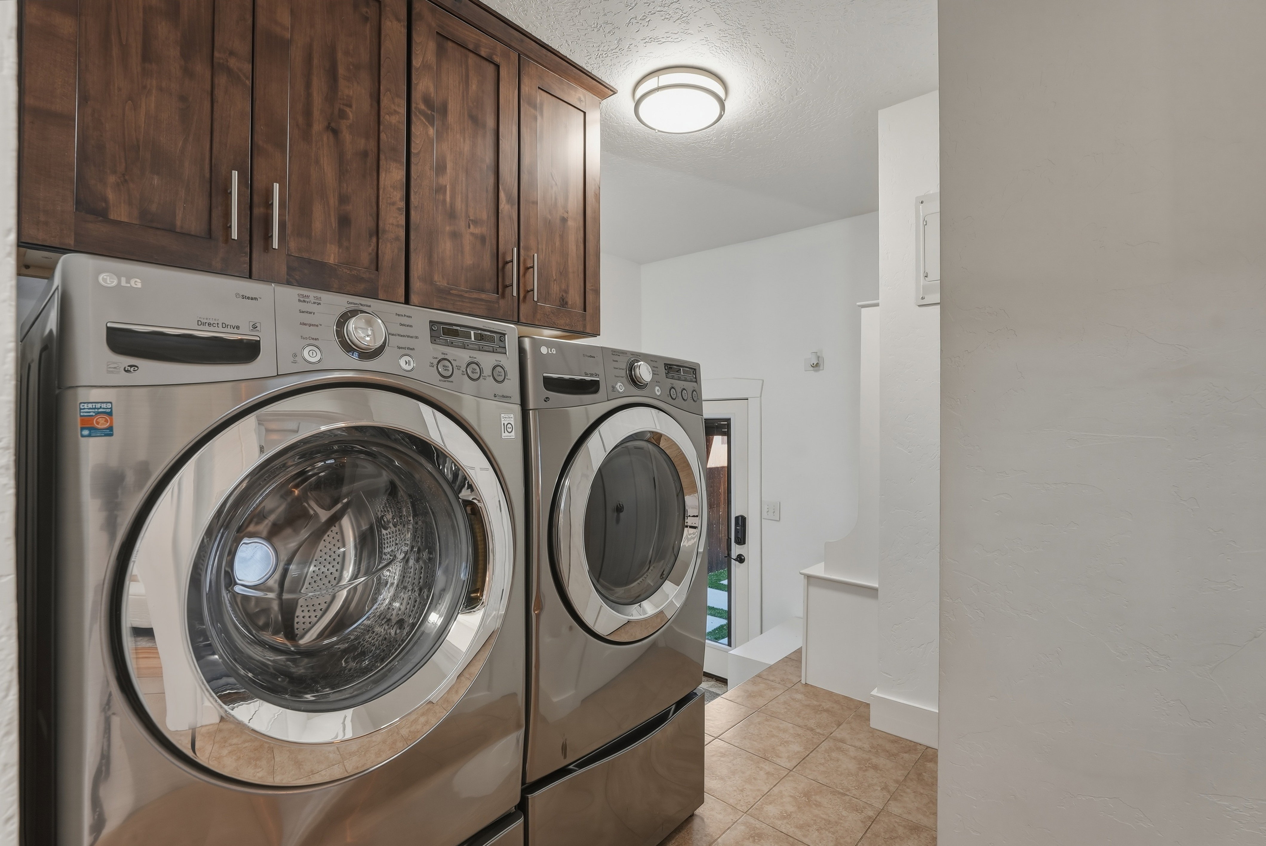 Laundry area featuring dark wood-finish cabinetry, tile flooring, and a contemporary ceiling light fixture