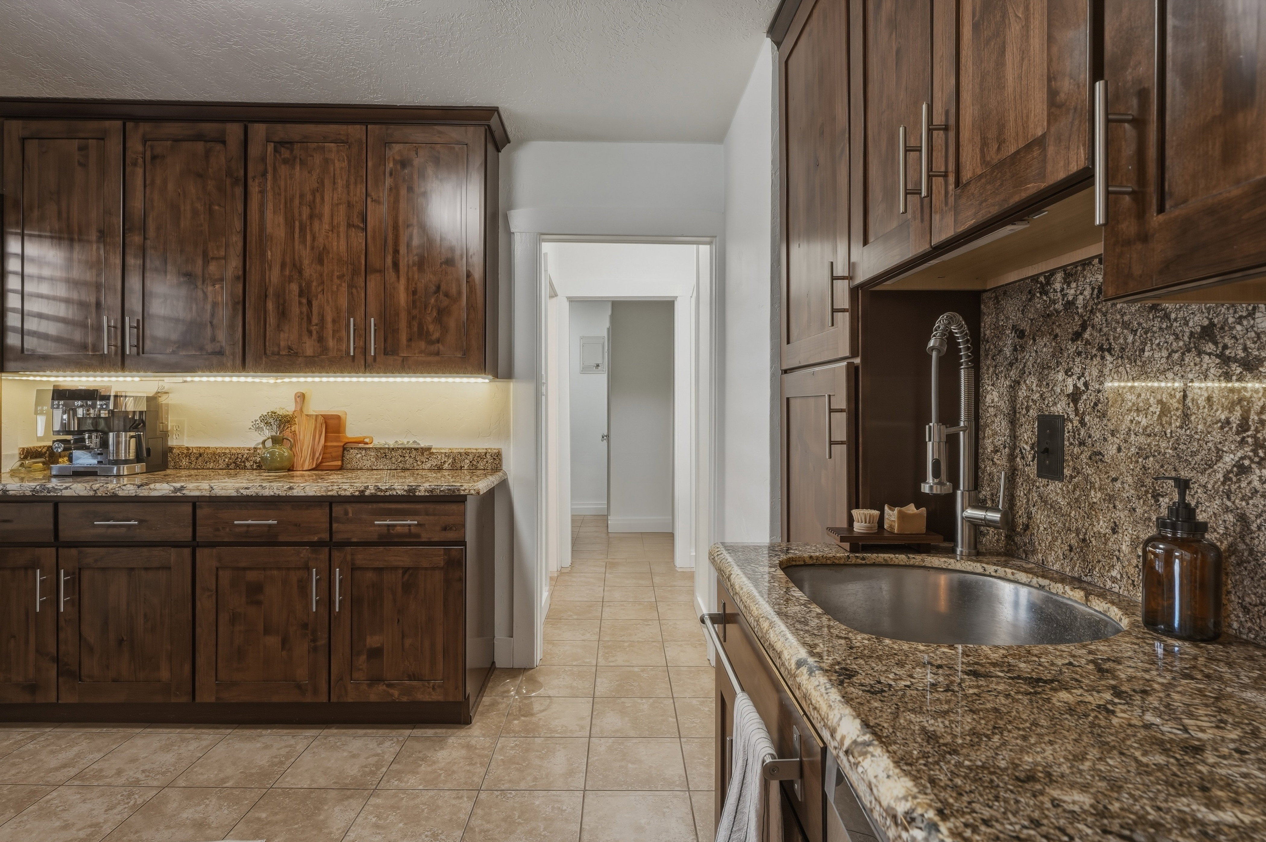 Kitchen featuring wood cabinetry, granite countertops, tile flooring, an undermount sink, and a pull-down faucet