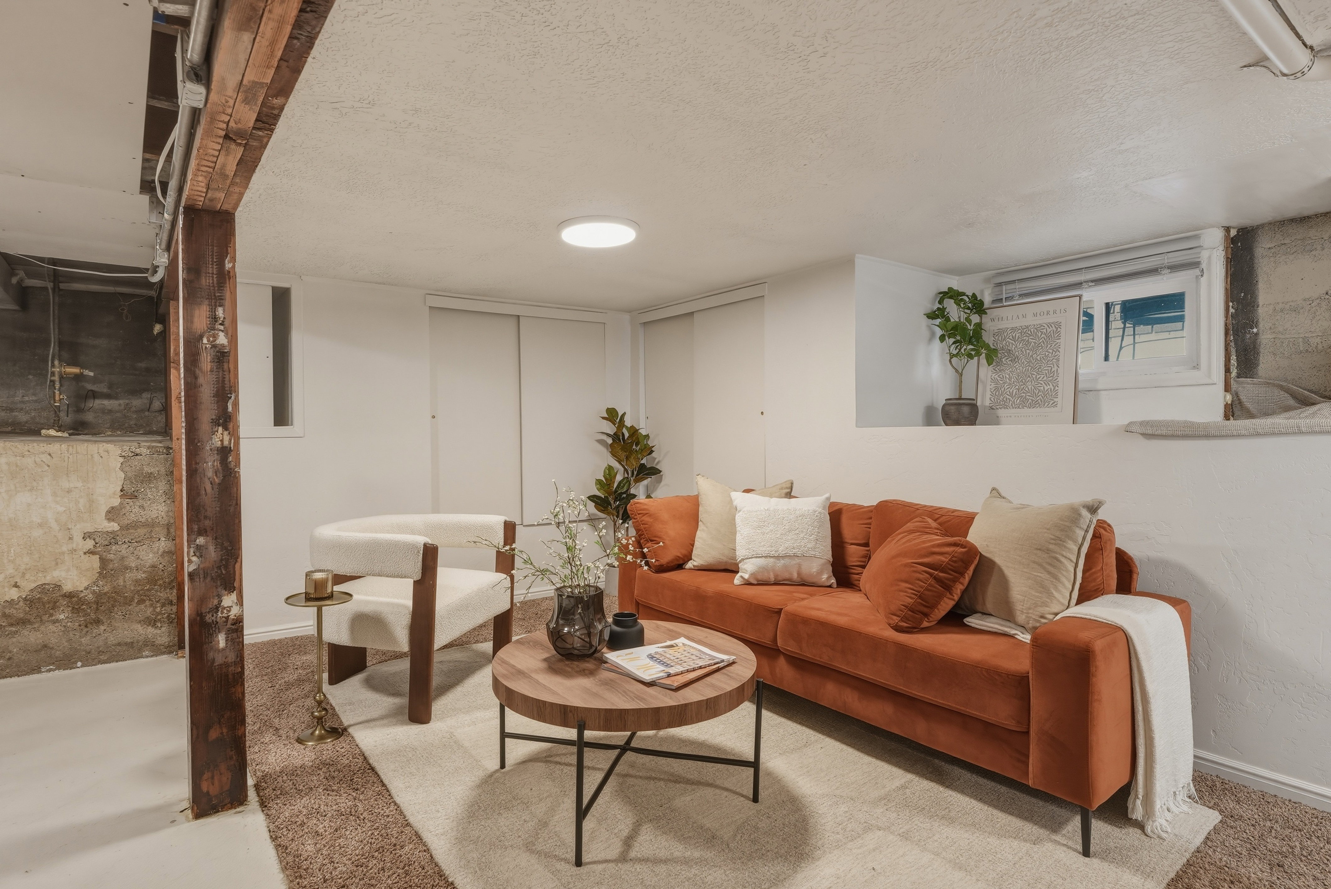 Finished lower level offering an exposed wood support beam, recessed lighting, and a window well for natural illumination