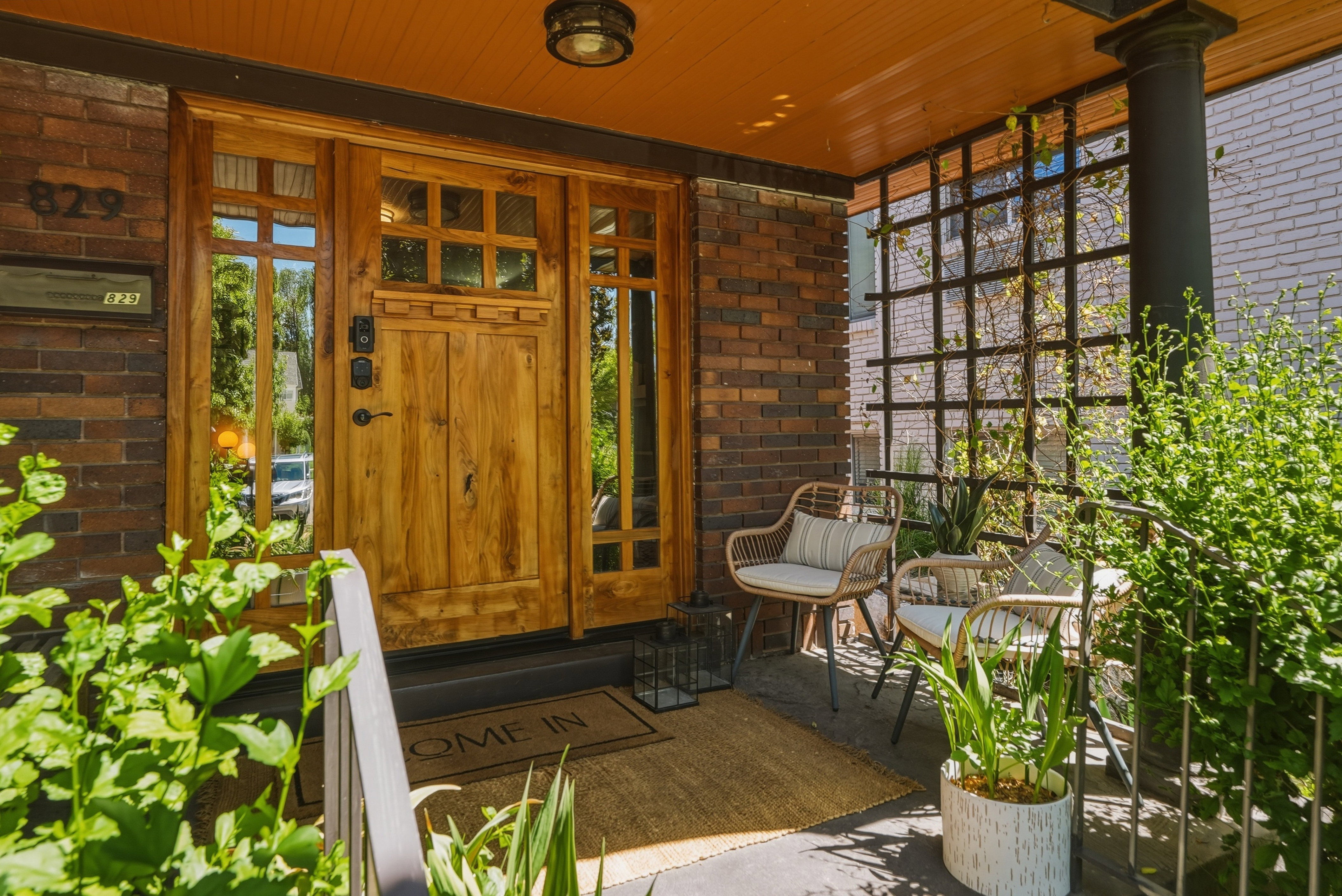 Front entrance featuring a paneled wood door with sidelights, brick façade, and a dark lattice privacy screen