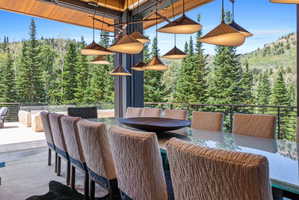 Dining area featuring a large rectangular table, upholstered chairs, and multiple pendant light fixtures