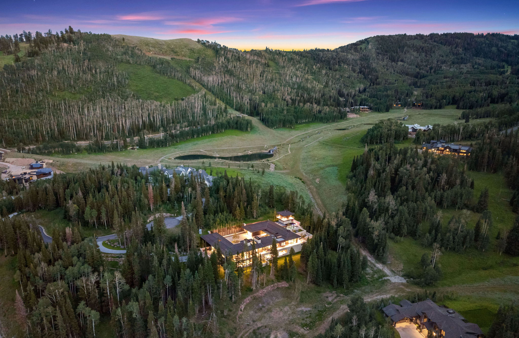 Sprawling mountain estate featuring extensive exterior lighting, multiple terraces, and a stone driveway