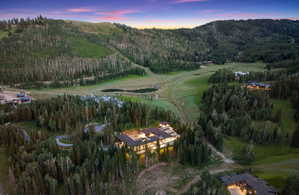 Sprawling mountain estate featuring extensive exterior lighting, multiple terraces, and a stone driveway