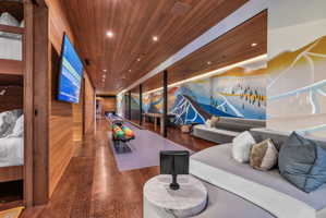 Recreational space featuring a built-in bowling lane, wood-finish flooring, wood plank ceiling, and illuminated wall art