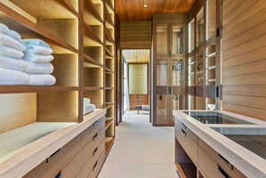 Custom closet system featuring wood-finish cabinetry, integrated lighting, and glass-front display cases