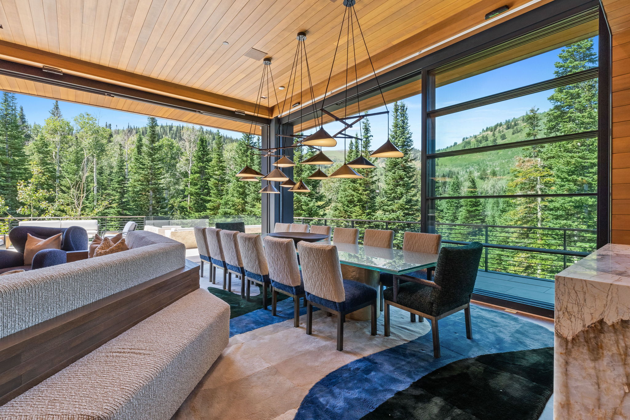Expansive dining area featuring floor-to-ceiling windows, a wood-paneled ceiling, and a linear multi-pendant light fixture