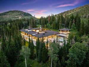 Grand mountain estate featuring extensive glass walls, multiple balconies, a distinct observation tower, and an integrated outdoor pool