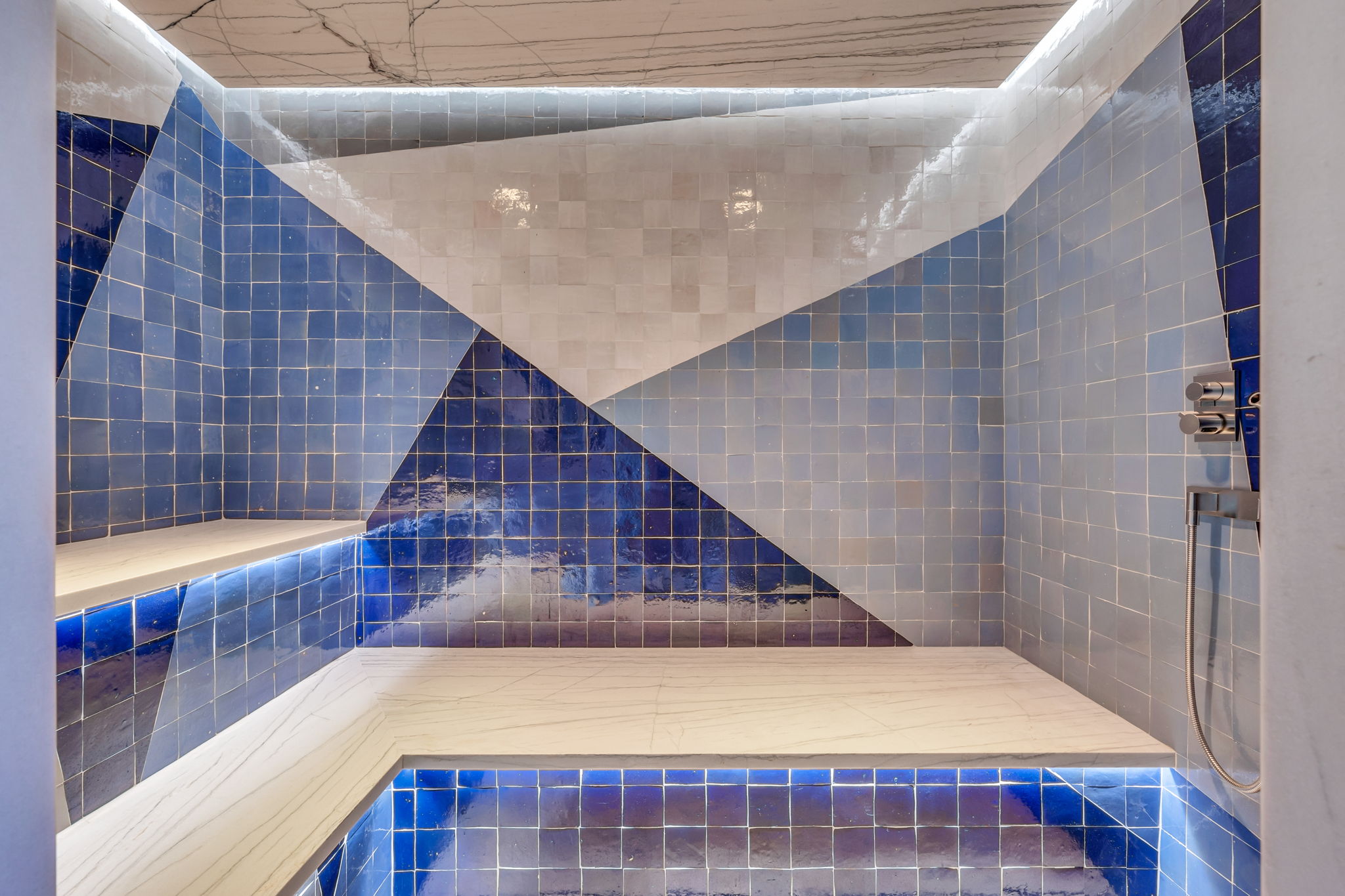 Custom tiled shower enclosure featuring a geometric pattern of blue and white square tiles