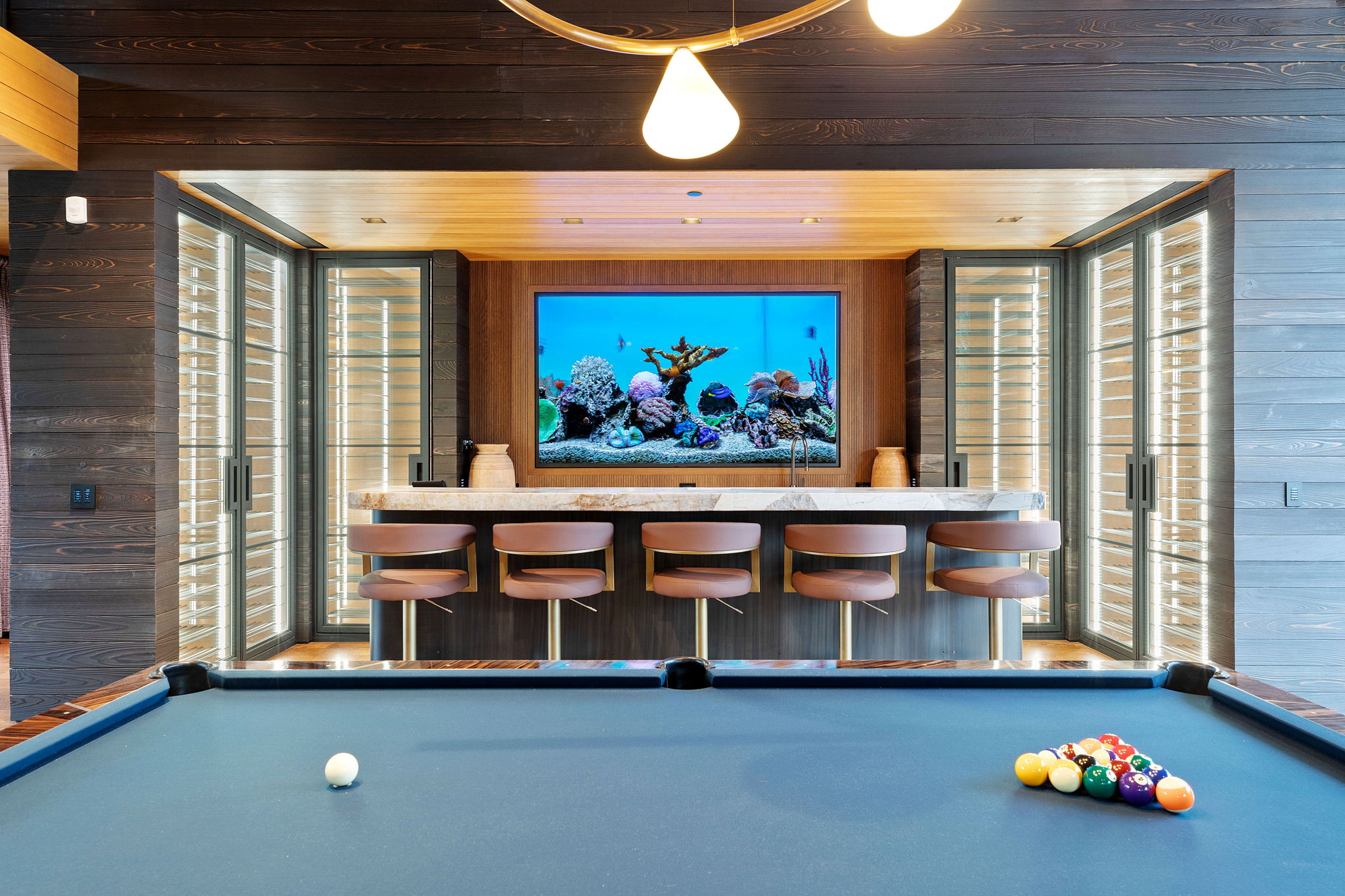 Entertainment space featuring a custom bar with a stone countertop, built-in aquarium, and a billiards table