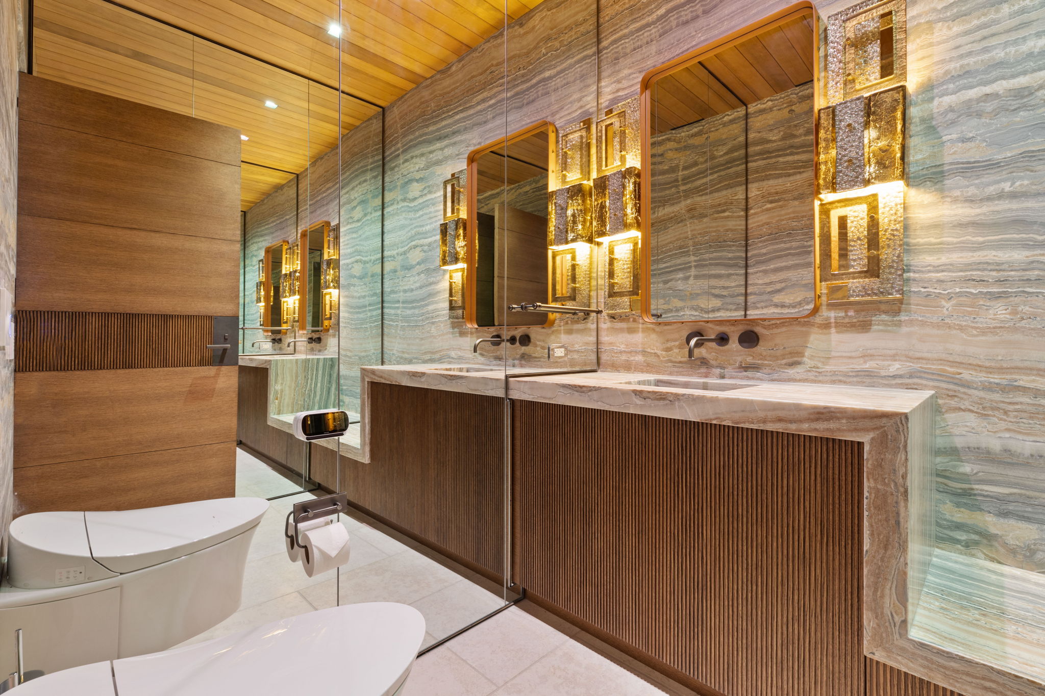 Contemporary bathroom featuring dual vanity with stone countertops, ribbed wood-finish cabinetry, and integrated sinks