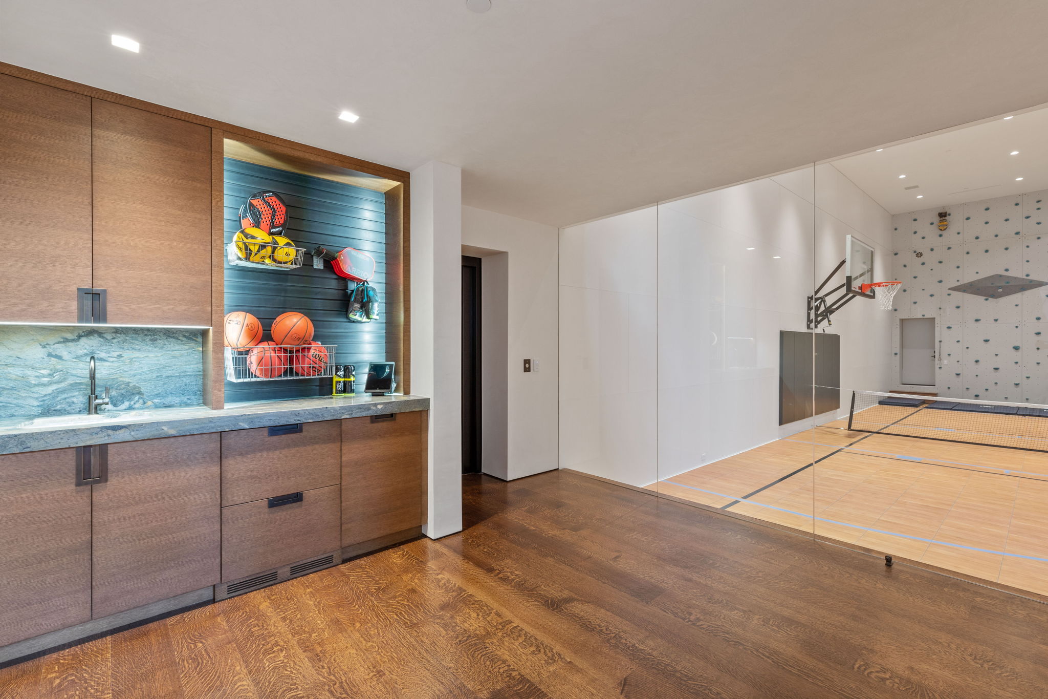 Indoor recreation court with light wood-finish flooring and a basketball hoop