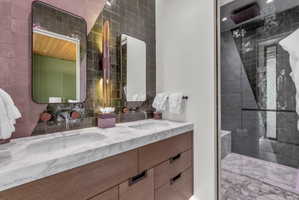 Dual vanity with wood-finish cabinetry, white marble countertop, and undermount sinks