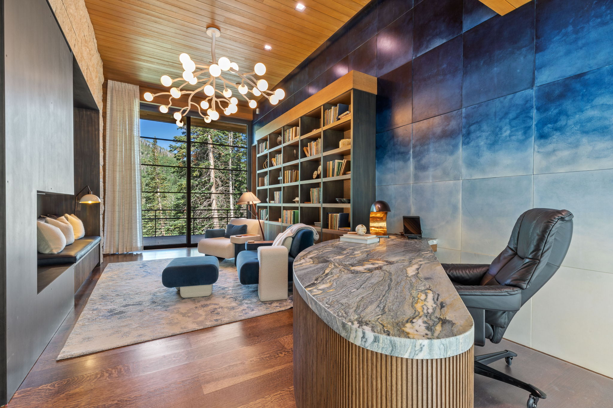 Spacious room featuring rich wood-finish flooring, a full-height window overlooking mature trees, and a built-in window seat with integrated lighting