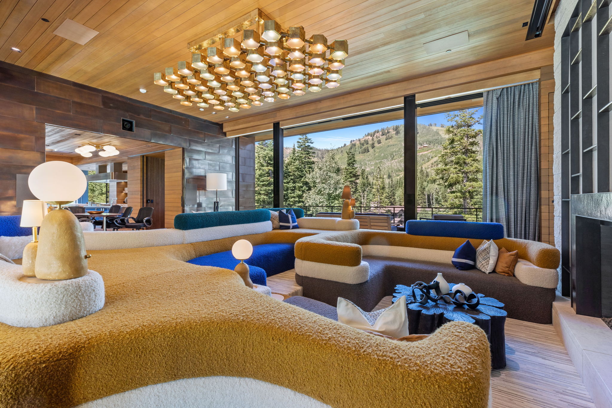 Expansive living area featuring a wood-panel ceiling and a large, multi-paneled chandelier