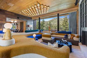 Expansive living area featuring a wood-panel ceiling and a large, multi-paneled chandelier