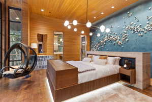Hardwood flooring and wall paneling complement a ceiling with recessed lighting