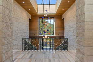 Grand hallway with natural stone walls, wood-finish ceiling, and a large skylight