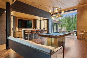 Expansive entertainment space featuring wood-finish flooring, a built-in wet bar with stone countertop, a billiards table, and a suspended swing seat