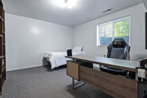 Carpeted room with a built-in wood-finish shelving unit, a window with horizontal blinds, and recessed lighting
