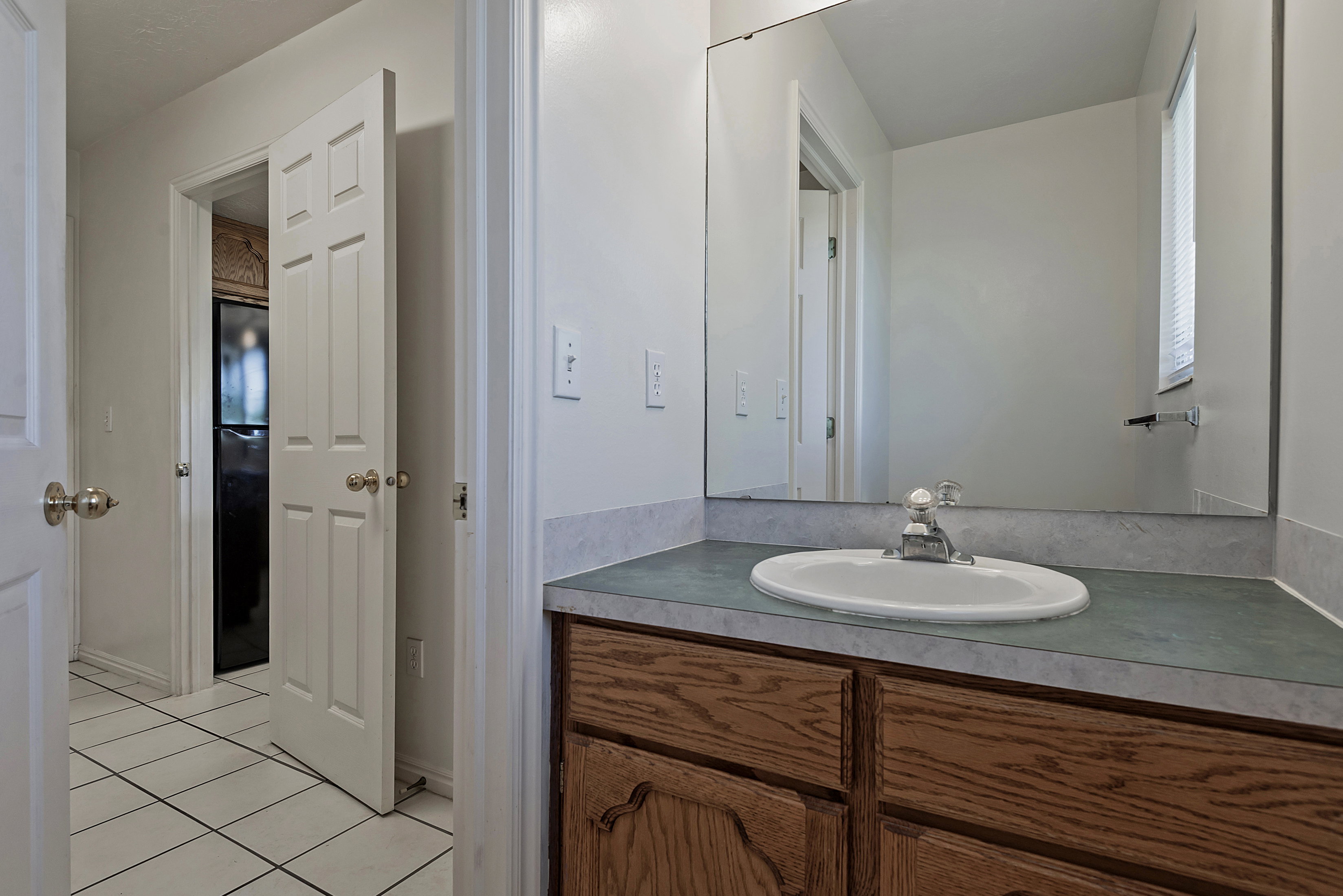 Vanity with an integrated oval sink, laminate countertop, and wood-finish cabinetry