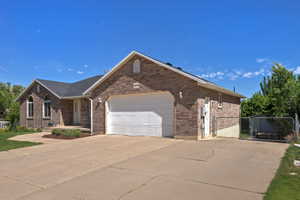 Brick exterior with a prominent two-car garage, rounded front windows, a covered entry, and a side chain-link fence