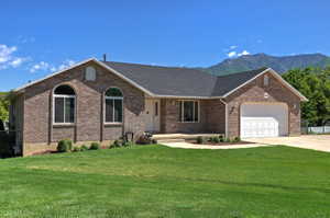 Brick exterior residence featuring a dark shingle roof, arched windows, and an attached two-car garage