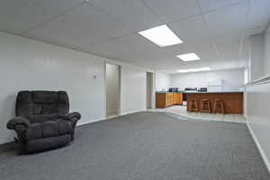 Spacious open-concept room featuring gray carpeting, a suspended ceiling with recessed lighting, and a white interior wall finish