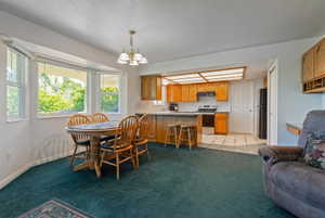 Bright dining area featuring a bay window, a breakfast bar, and a kitchen with wood cabinetry