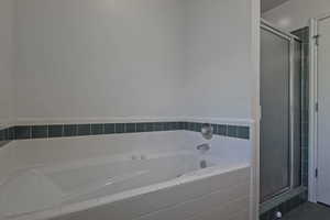 White drop-in jetted bathtub with chrome fixtures and white tile surround