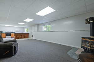 Spacious lower level featuring a modern stove fireplace with a tile hearth, a wood-finish bar, recessed lighting, wood-finish cabinetry, and white appliances