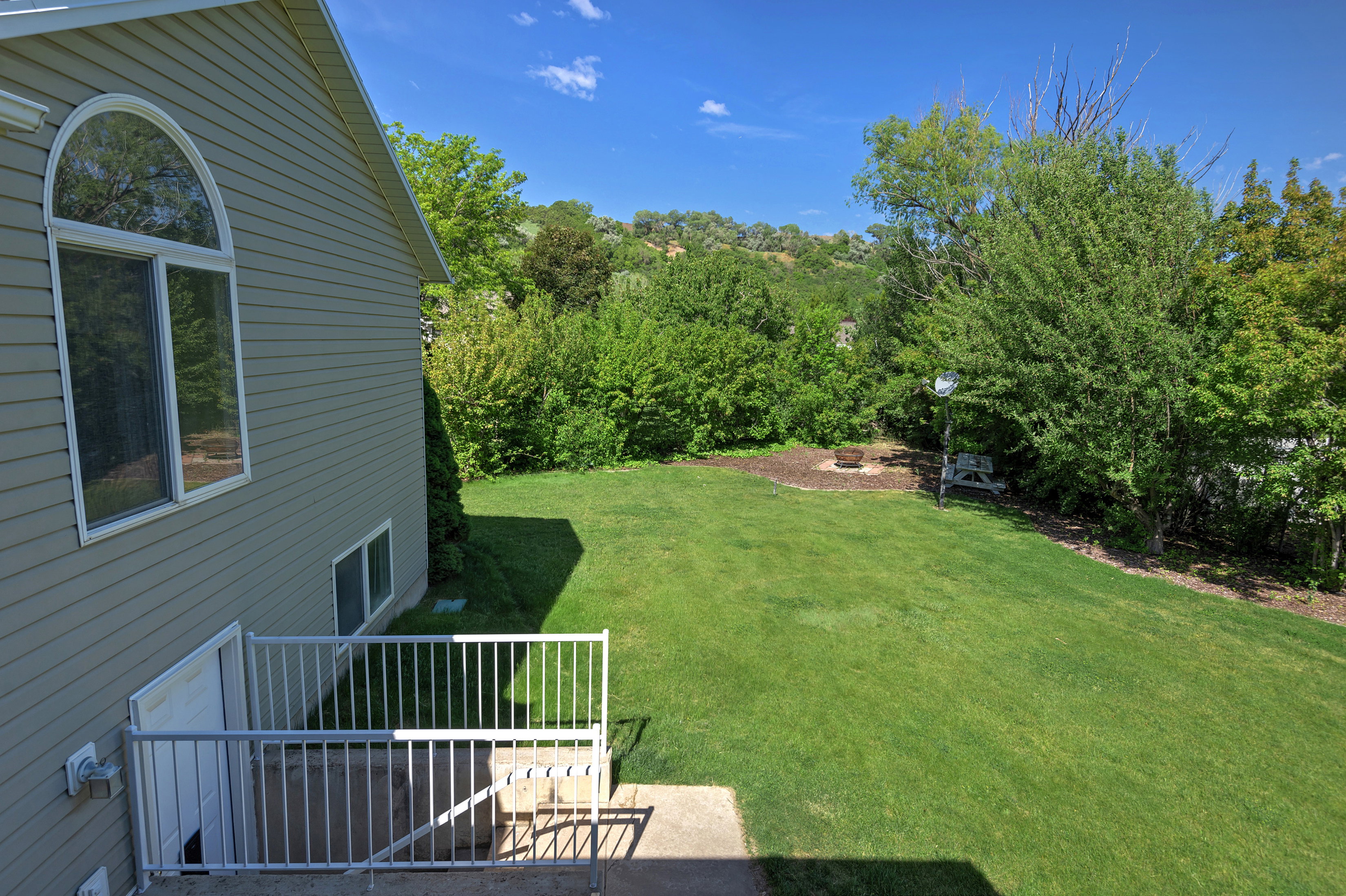 Expansive green lawn with mature trees and a dedicated fire pit area