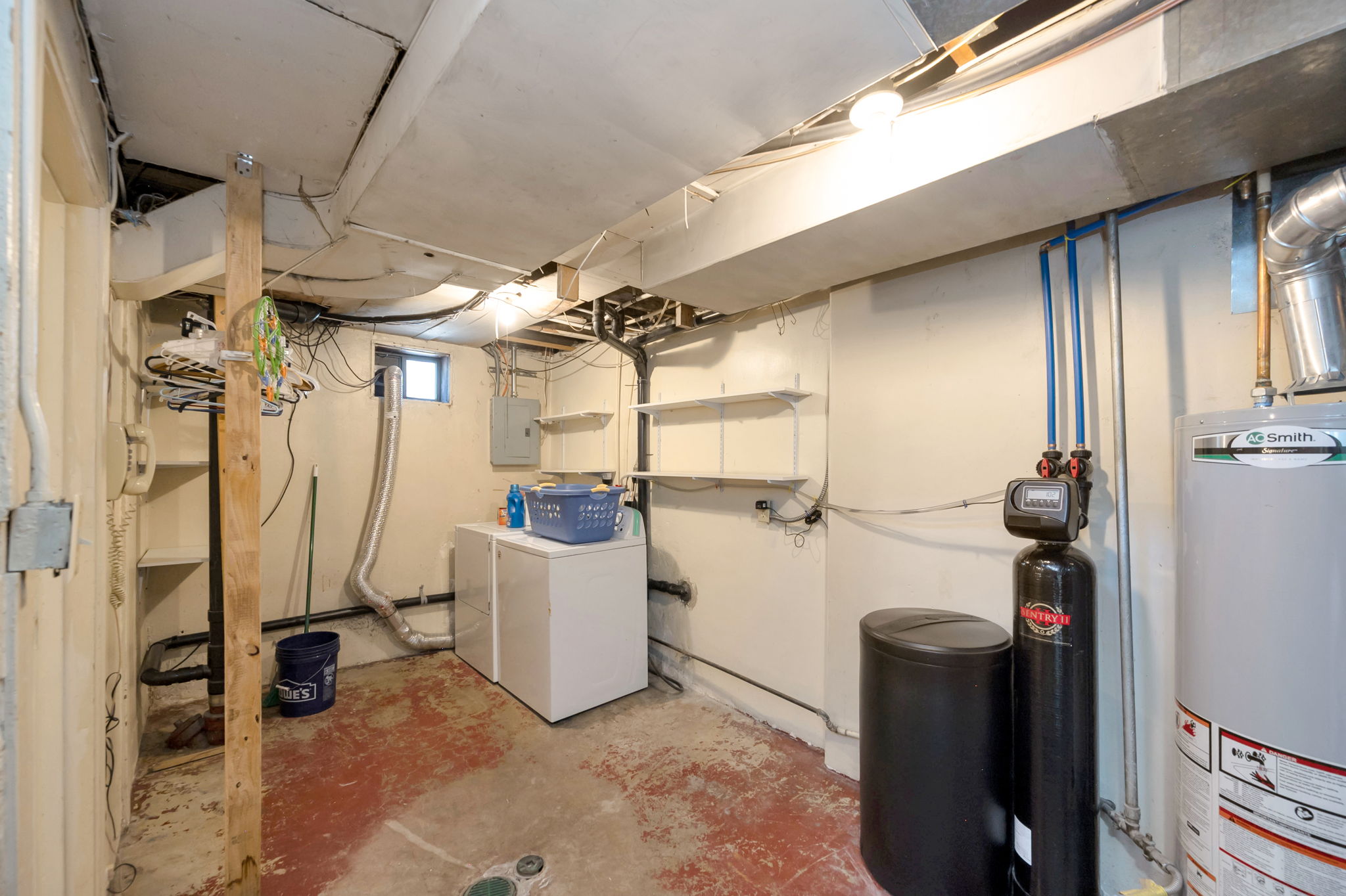 Utility room featuring a water heater, water treatment system, and built-in shelving
