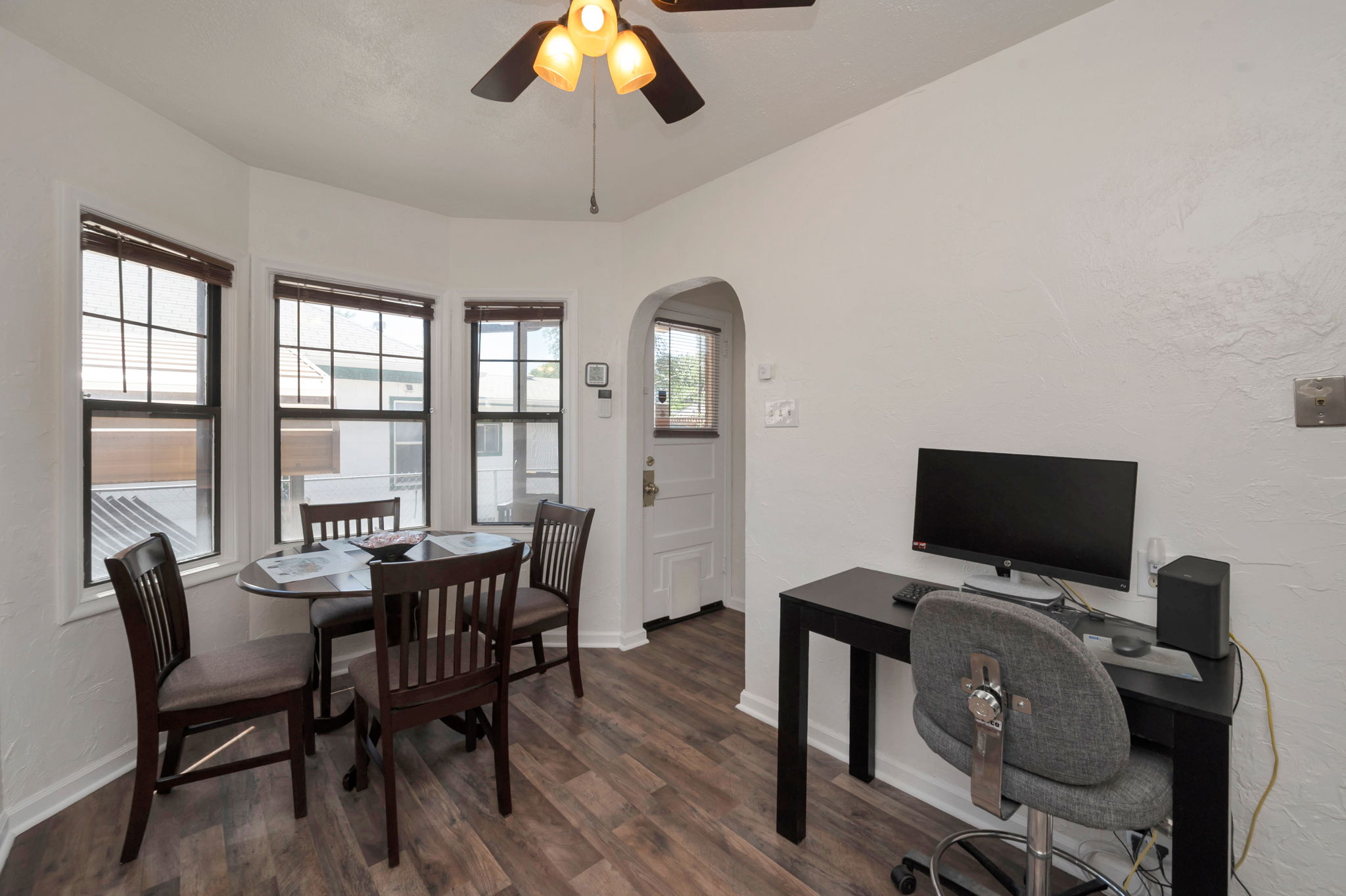 Dining area featuring wood-finish flooring, a bay window with multiple panes, and a ceiling fan with light fixture