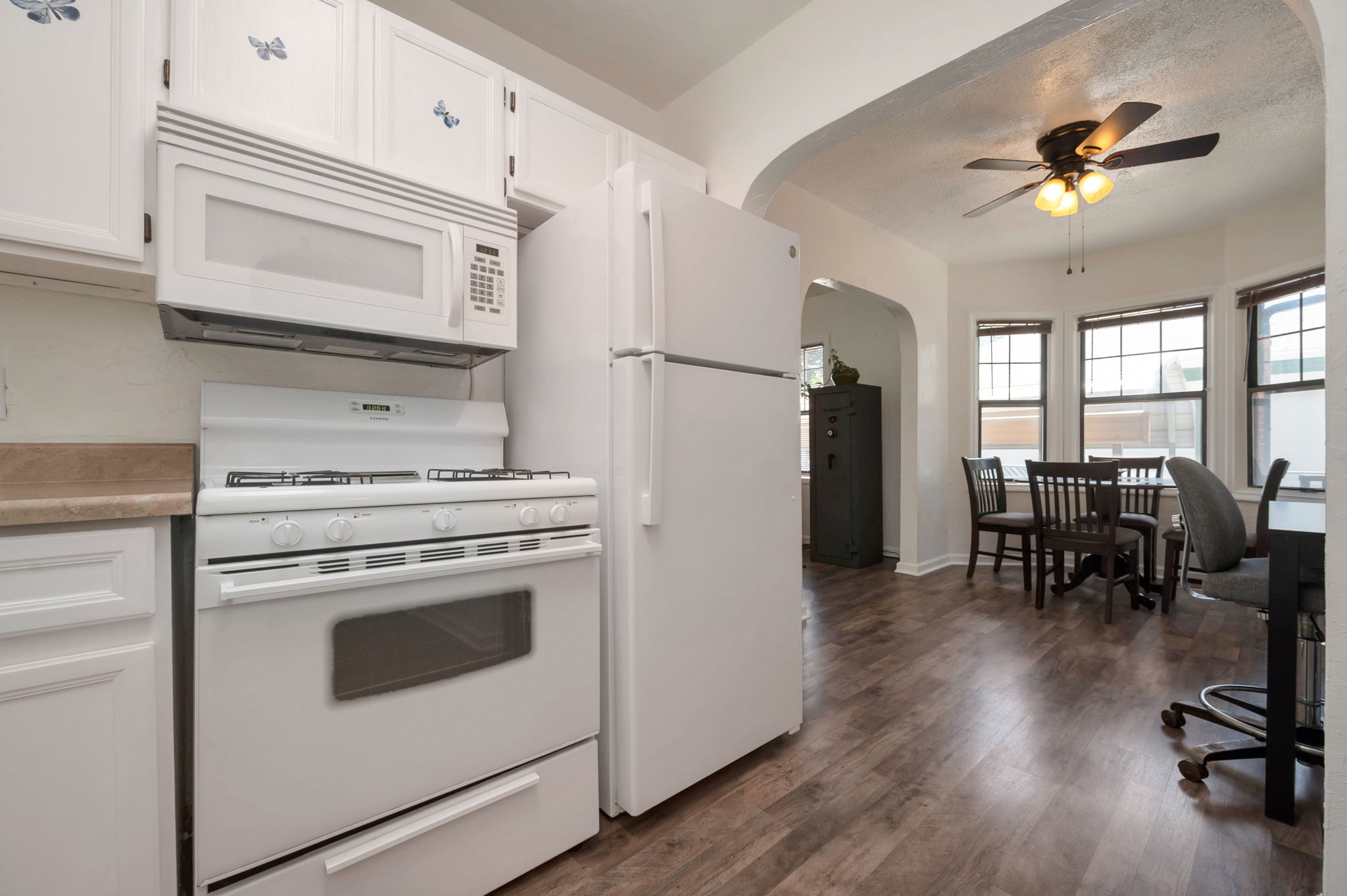 Kitchen area featuring white cabinetry, white appliances, and wood-finish flooring