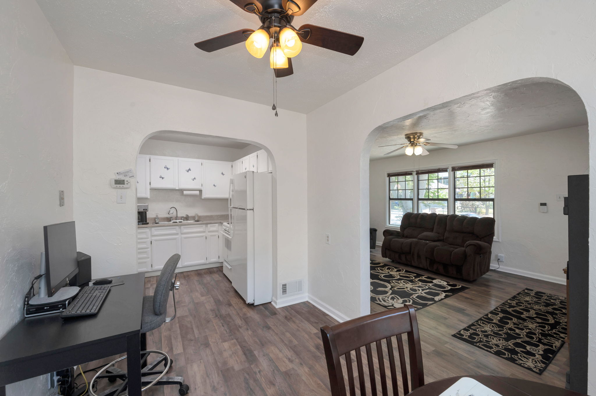 Open-concept living space featuring wood-finish flooring, white walls, and a ceiling fan