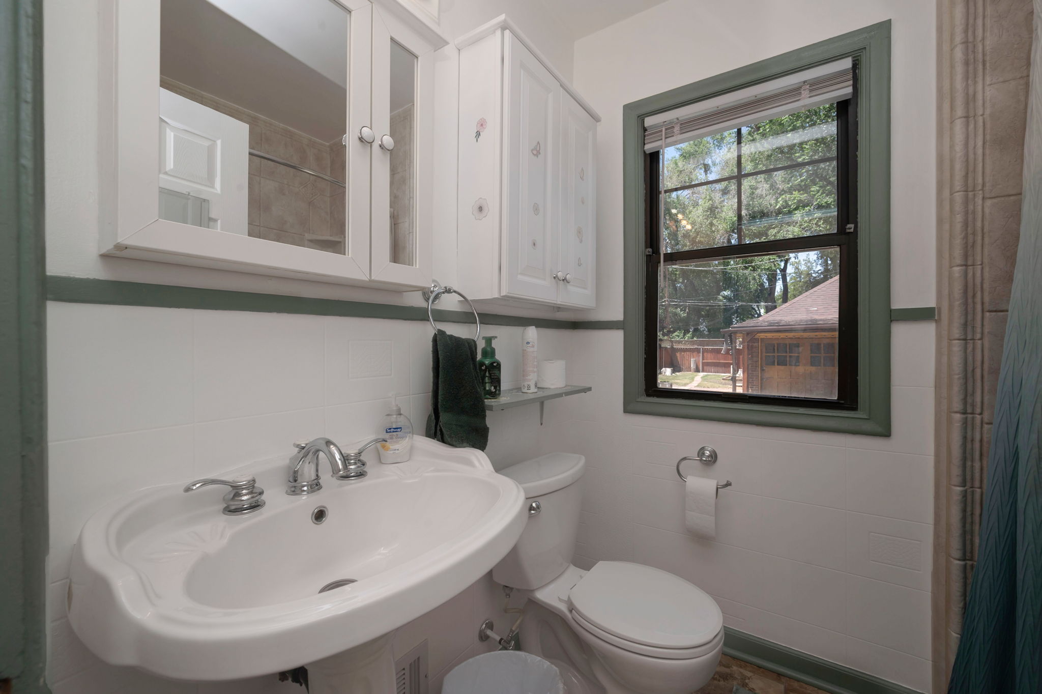 Pedestal sink with chrome fixtures, medicine cabinet with mirrored doors, and white paneled upper cabinetry