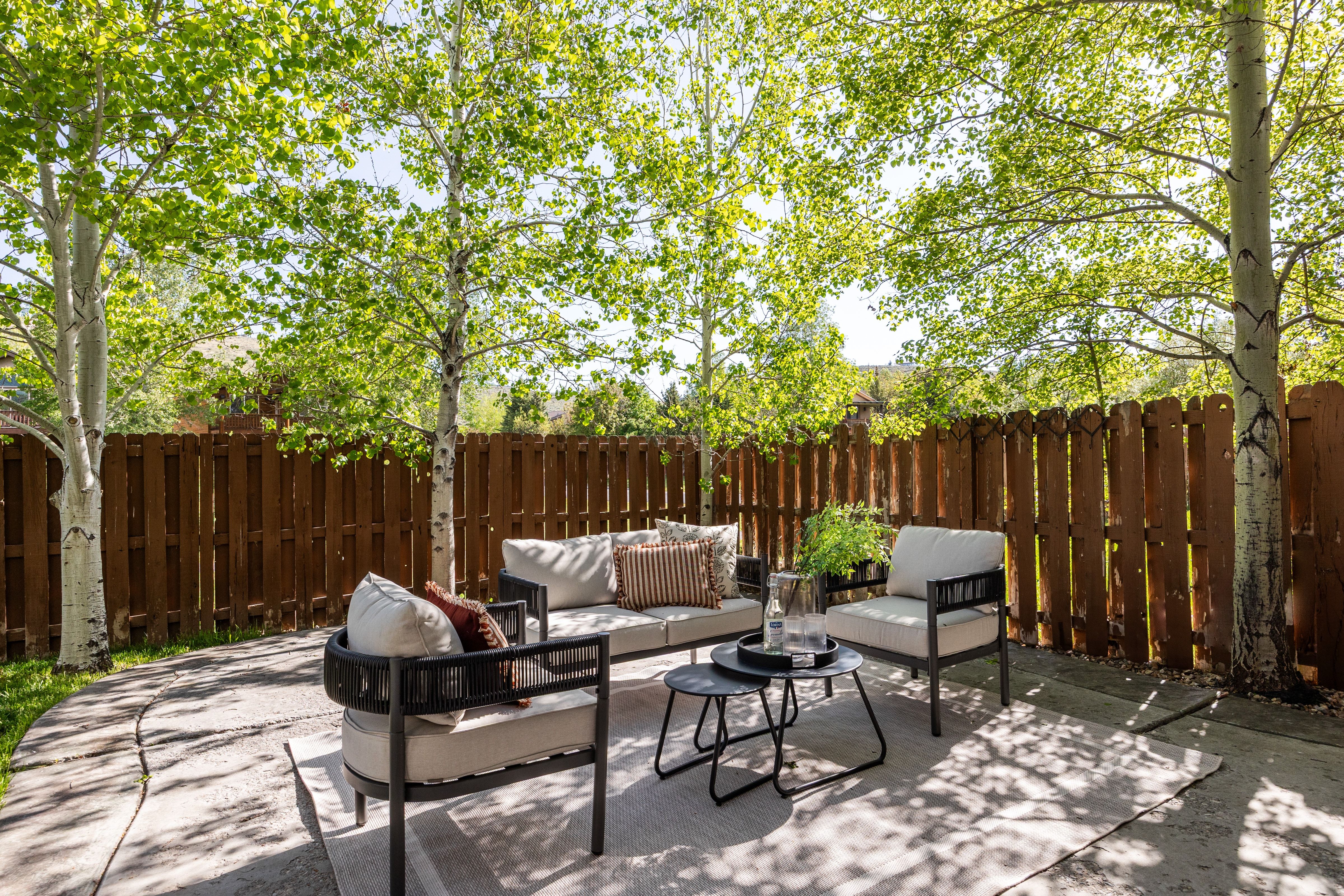 Private outdoor patio featuring a concrete surface, a perimeter wood fence, and mature deciduous trees