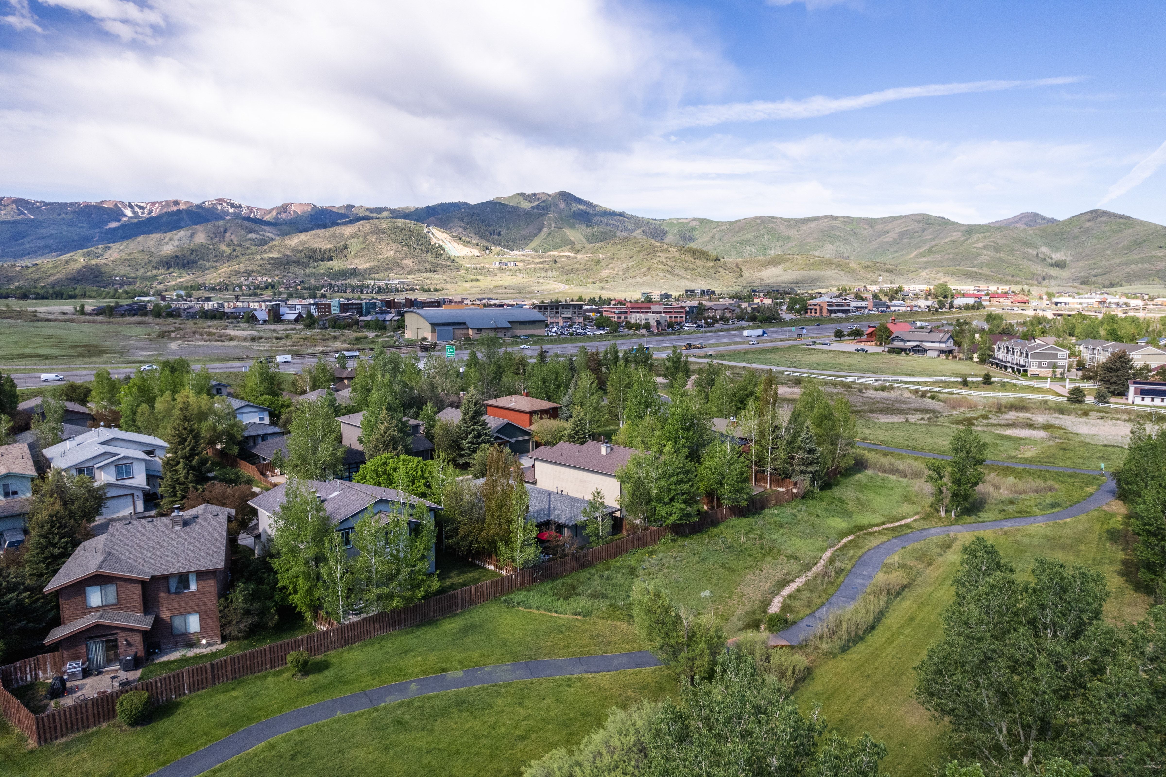 Aerial perspective showcasing a residential area with varied housing styles, mature trees, and a paved pathway system